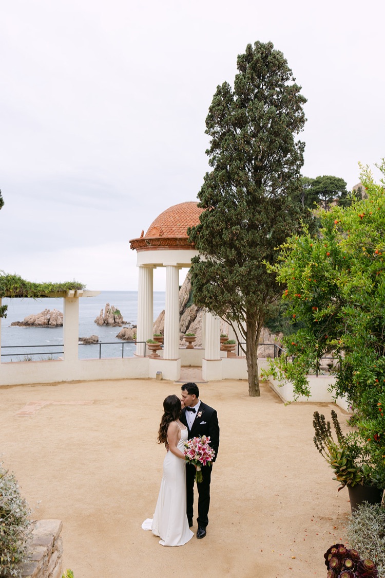 A couple embracing on the sand terrace in front of the Linnaeus Temple at Marimurtra Botanic Gardens, Blanes