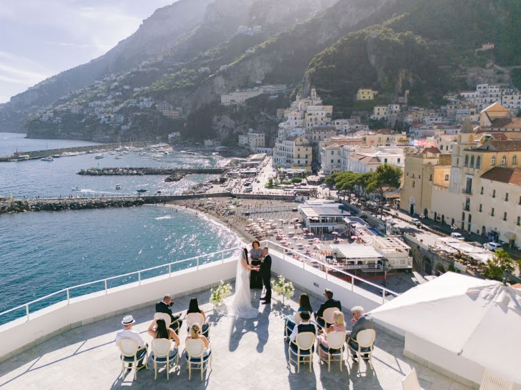 Aerial view of an elopement ceremony on the rooftop terrace of Hotel Marina Riviera on the Amalfi Coast above Amalfi's beach and cathedral