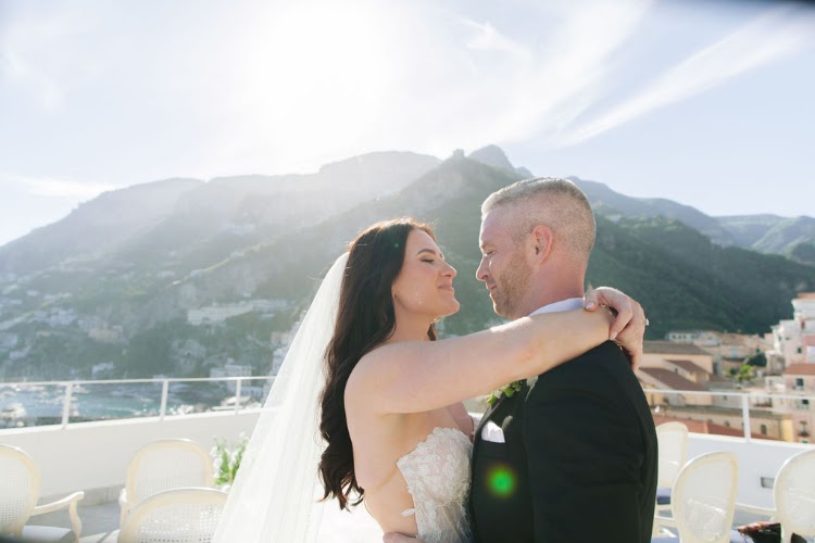 Newlyweds embracing forehead to forehead on the rooftop terrace of Hotel Marina Riviera on the Amalfi Coast with Amalfi mountain views