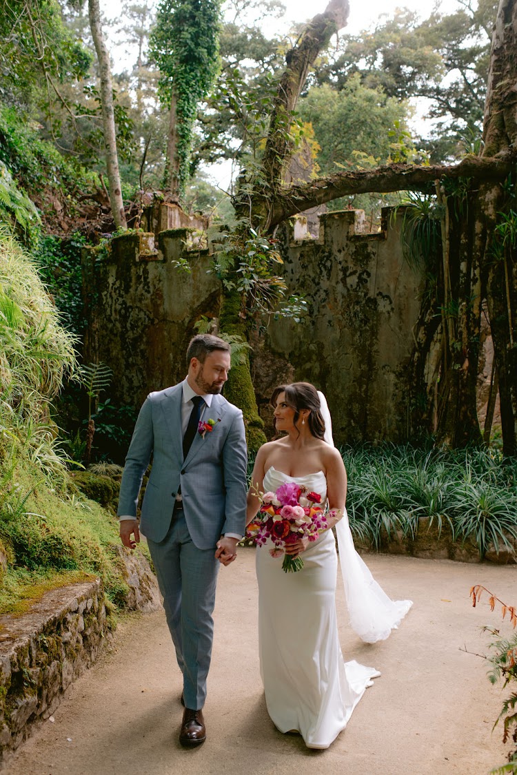 A groom and bride walking hand in hand along the garden path at Monserrate Palace in Sintra, Portugal