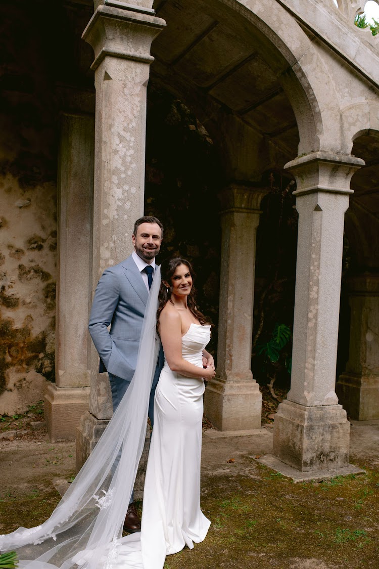 A couple posing under the stone arches of the ruined pavilion at Monserrate Palace in Sintra, Portugal