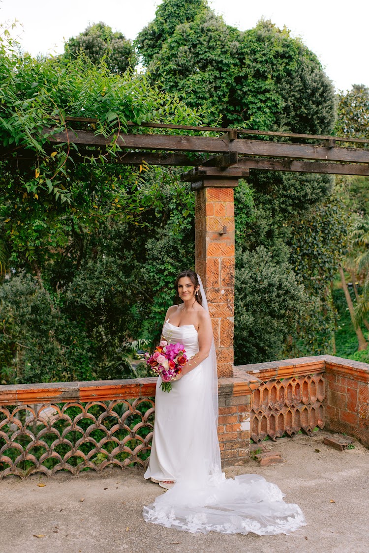 A bride in a flowing veil by a terracotta pergola in the gardens of Monserrate Palace in Sintra, Portugal