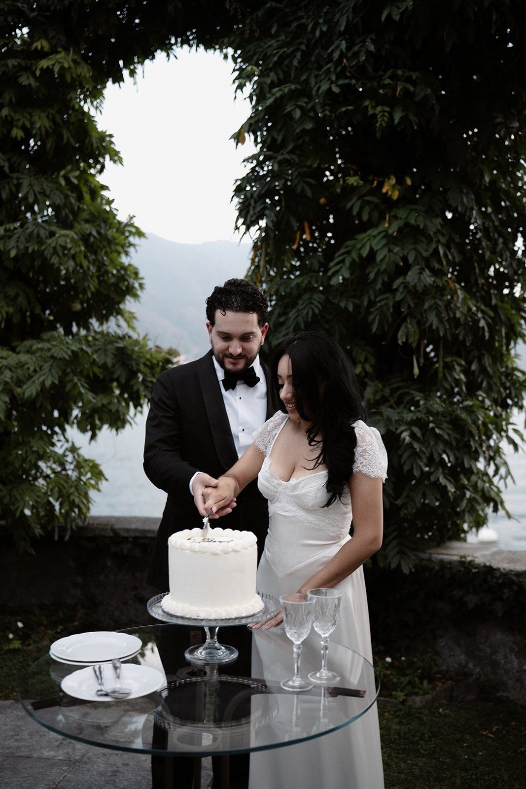 A couple cutting their wedding cake under a garden arch at Villa Noseda