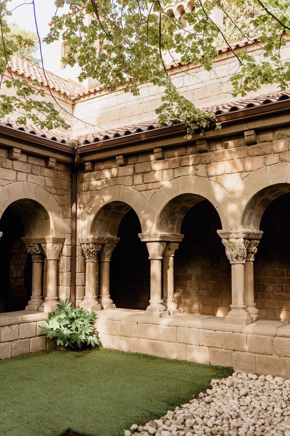 The stone cloister of the monastery at Poble Espanyol in Barcelona, with arches around a small lawn