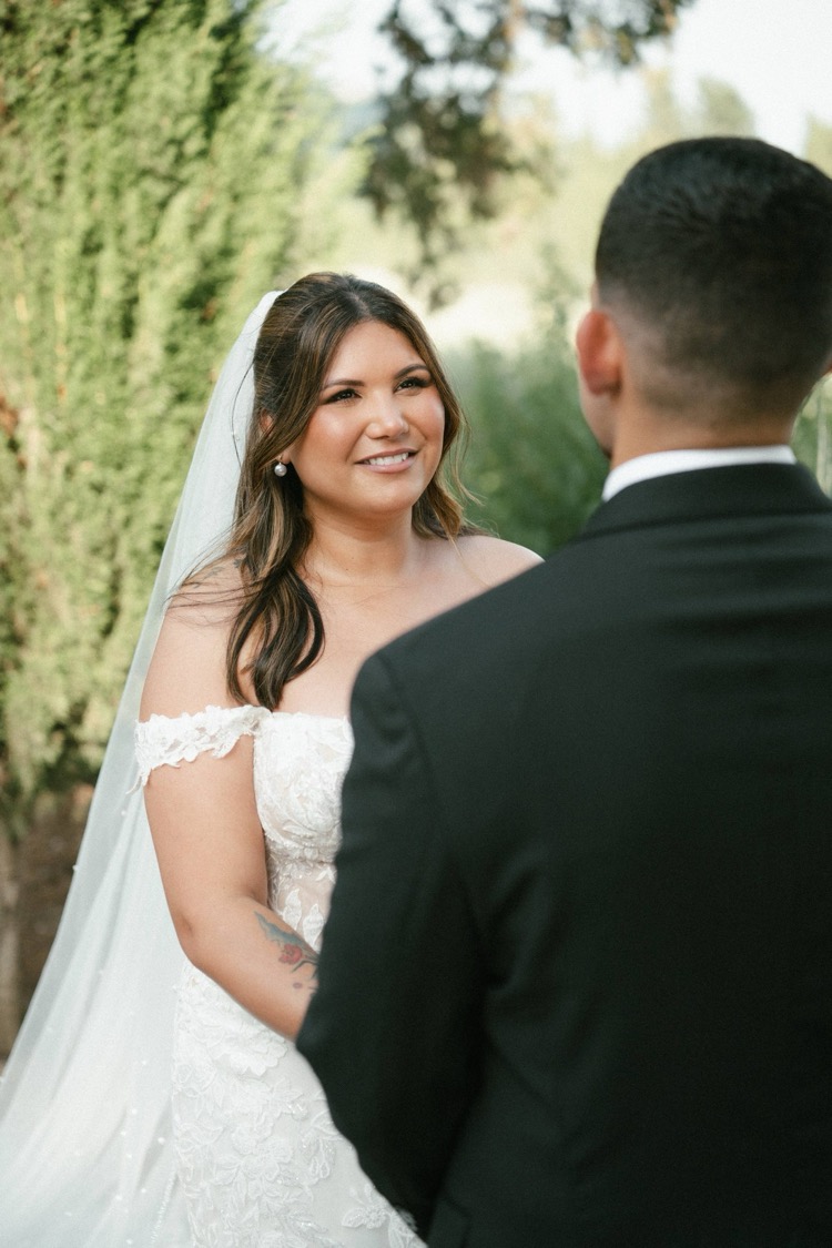 A bride smiling at her groom during the ceremony in the gardens of Villa Poggiano, Tuscany