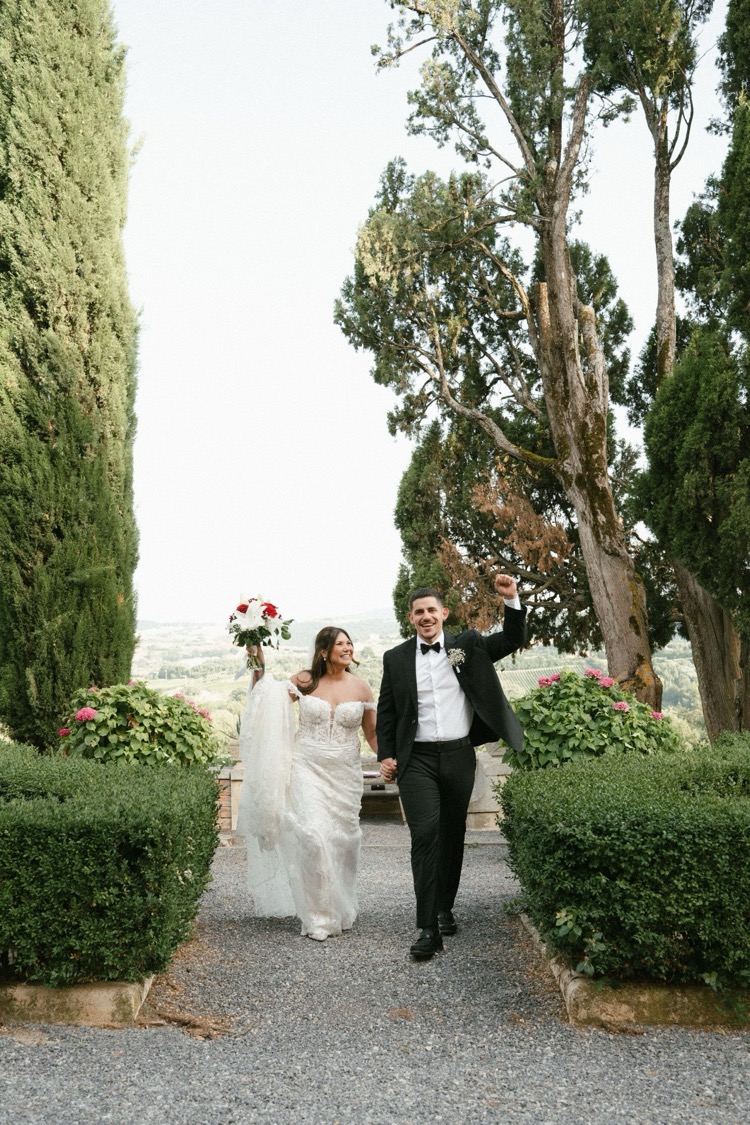 A joyful couple walking down the garden steps at Villa Poggiano, Tuscany, with hills in the distance