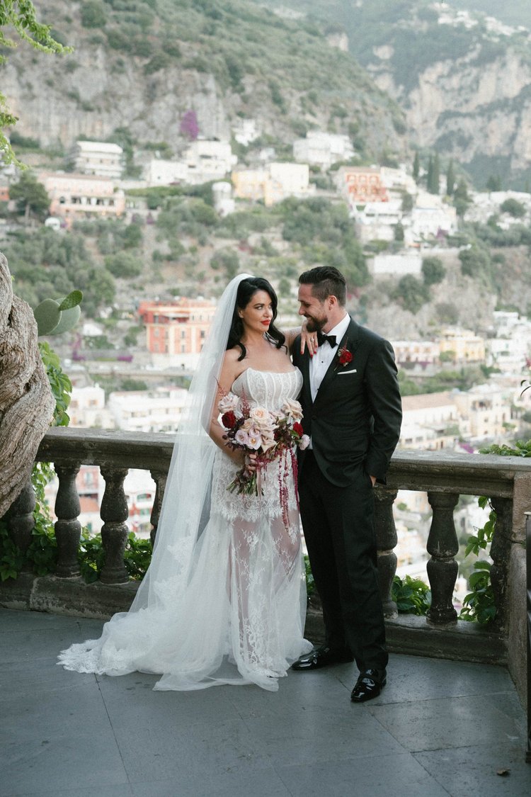 A couple on a balustrade terrace, with Positano behind