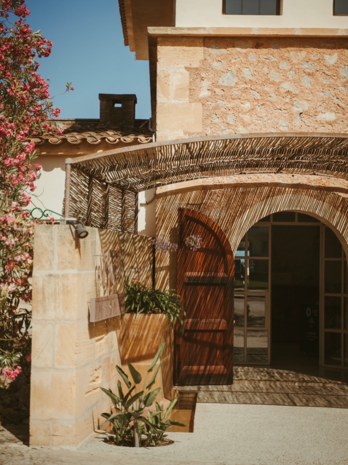 A stone courtyard with an arched wooden door and bougainvillea at Restaurant Sa Punta in Mallorca