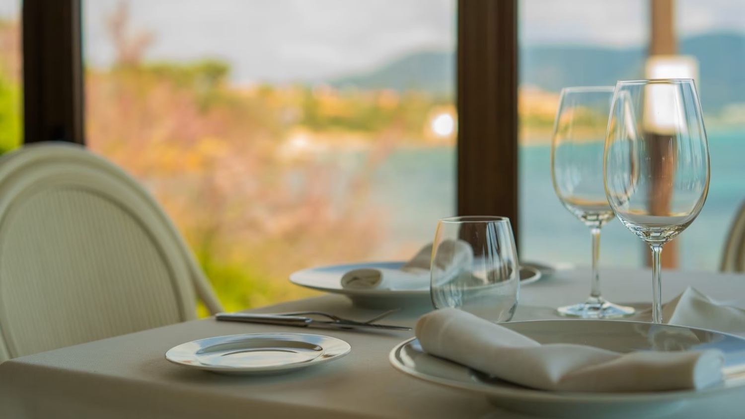 A table set with glasses on the terrace of Restaurant Sa Punta in Mallorca, with the coast behind