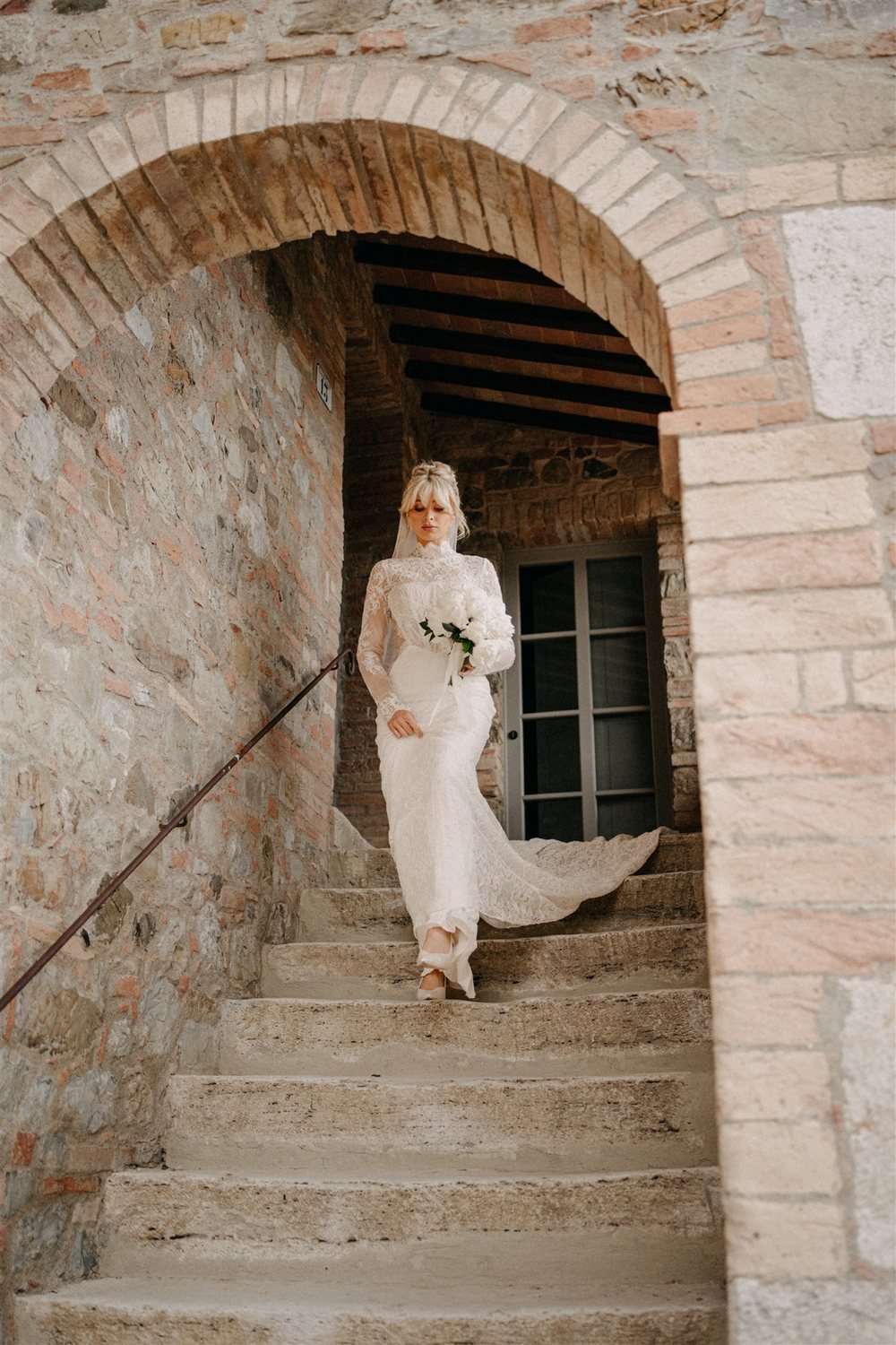 A bride under a stone arch at Sce Quirìc