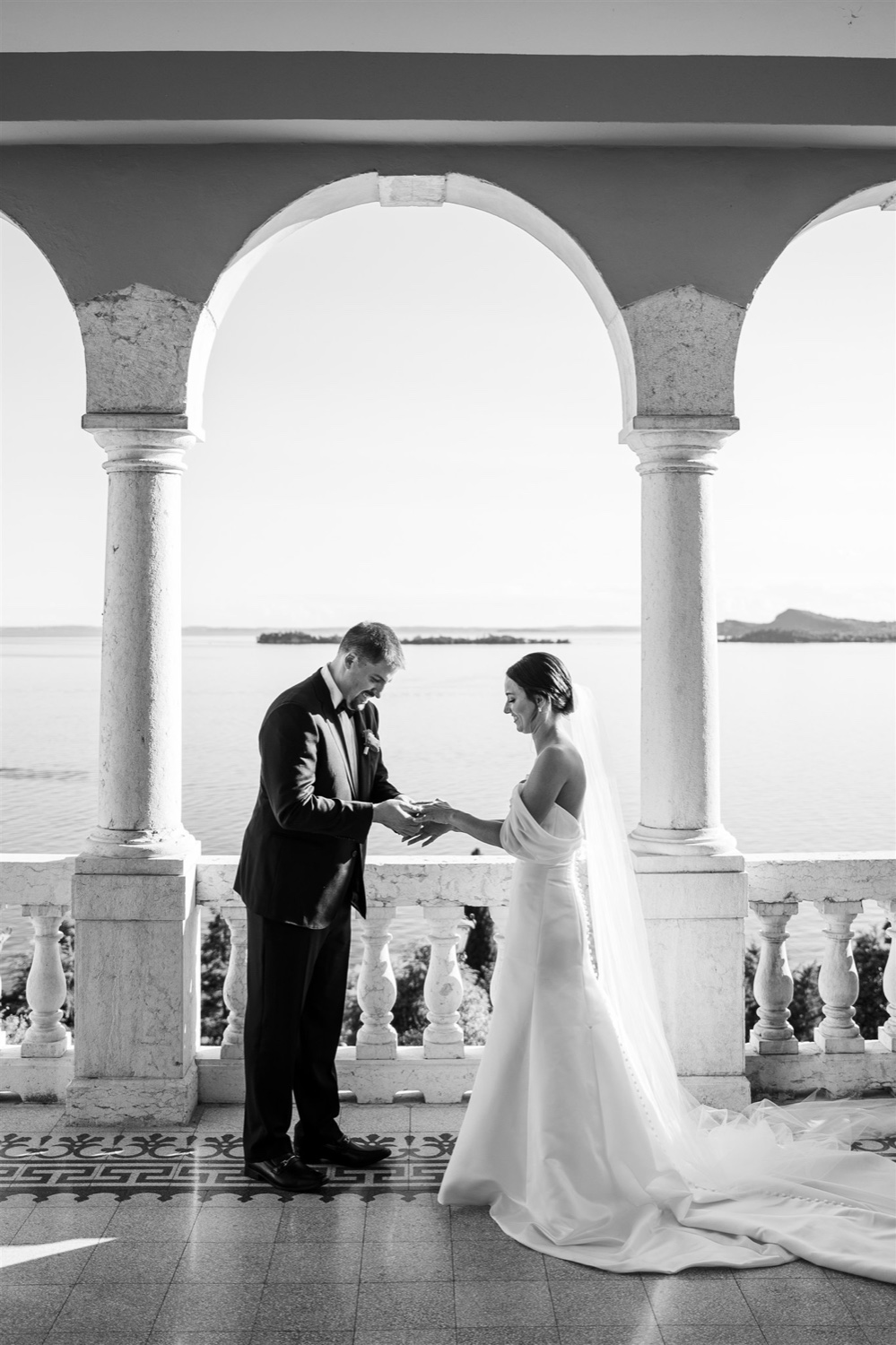 A black and white photo of a couple exchanging vows under the arches of the terrace at Villa del Sogno on Lake Garda