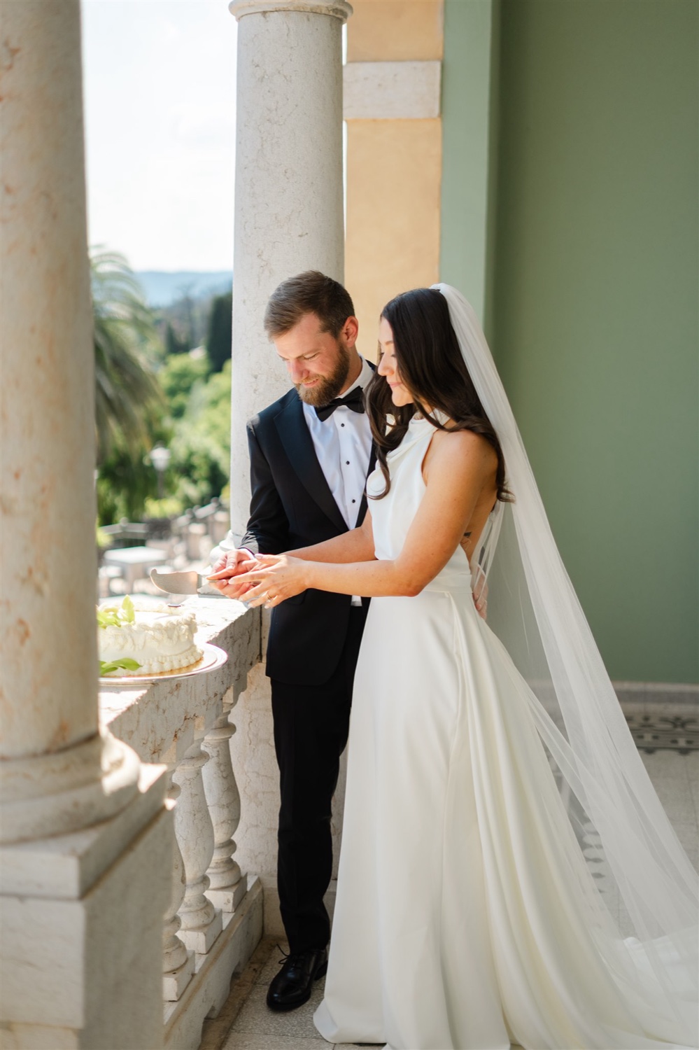 A couple cutting their wedding cake on the terrace of Villa del Sogno on Lake Garda
