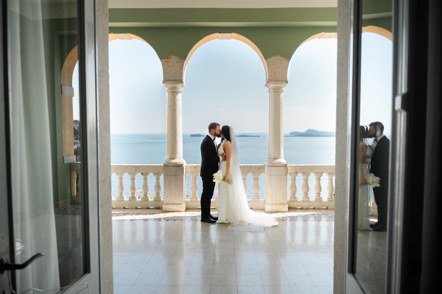 A black and white photo of a couple kissing under the arches of Villa del Sogno on Lake Garda