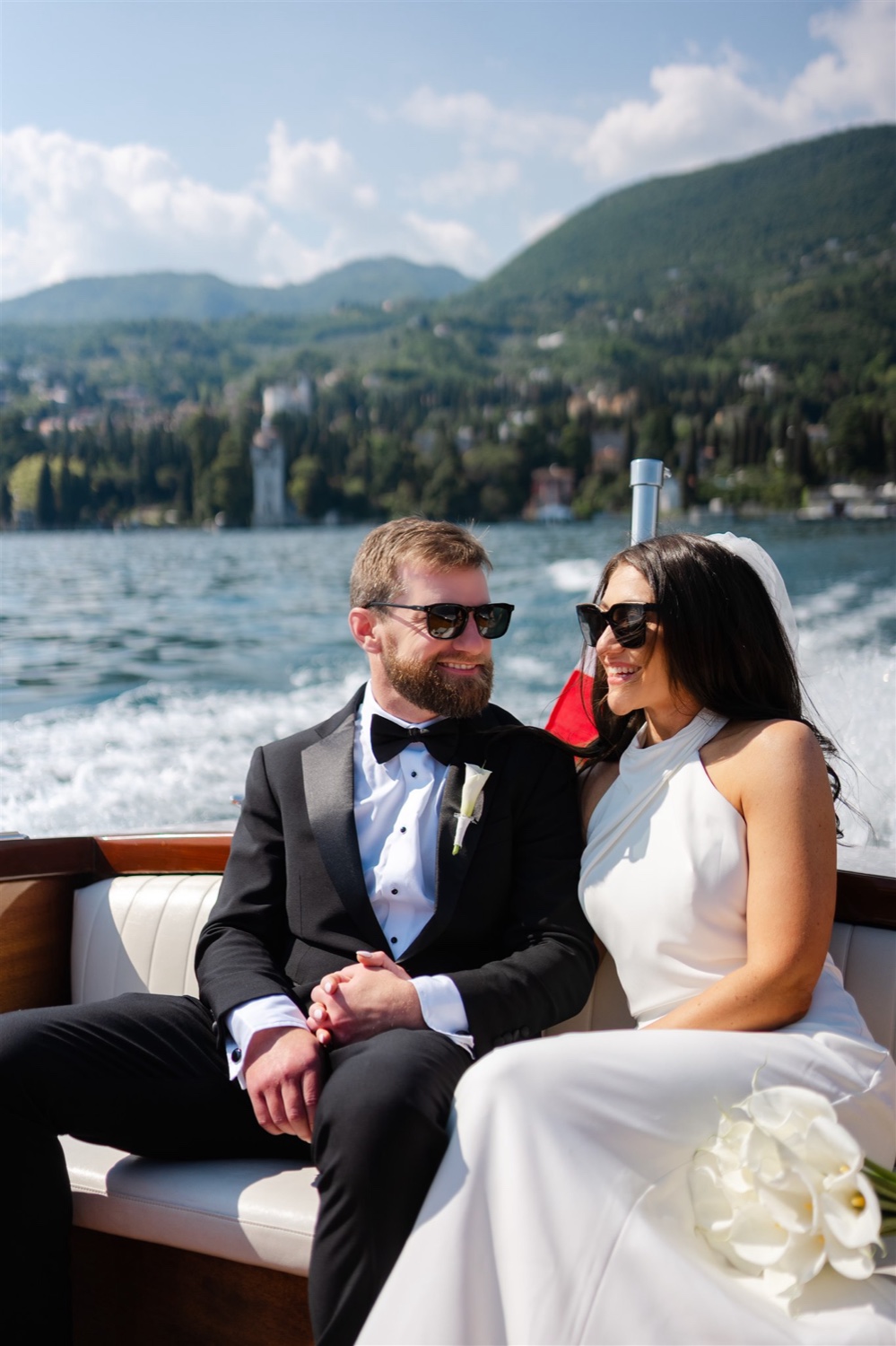 A couple on a wooden boat on Lake Garda, with the hills behind them