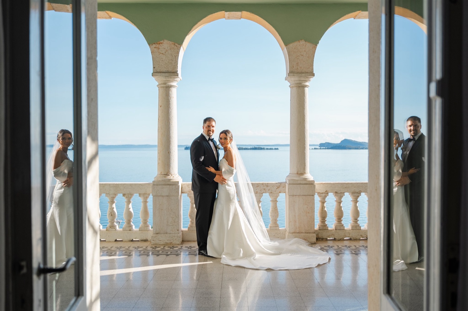A couple embracing on the arched terrace of Villa del Sogno on Lake Garda, framed by the open doors
