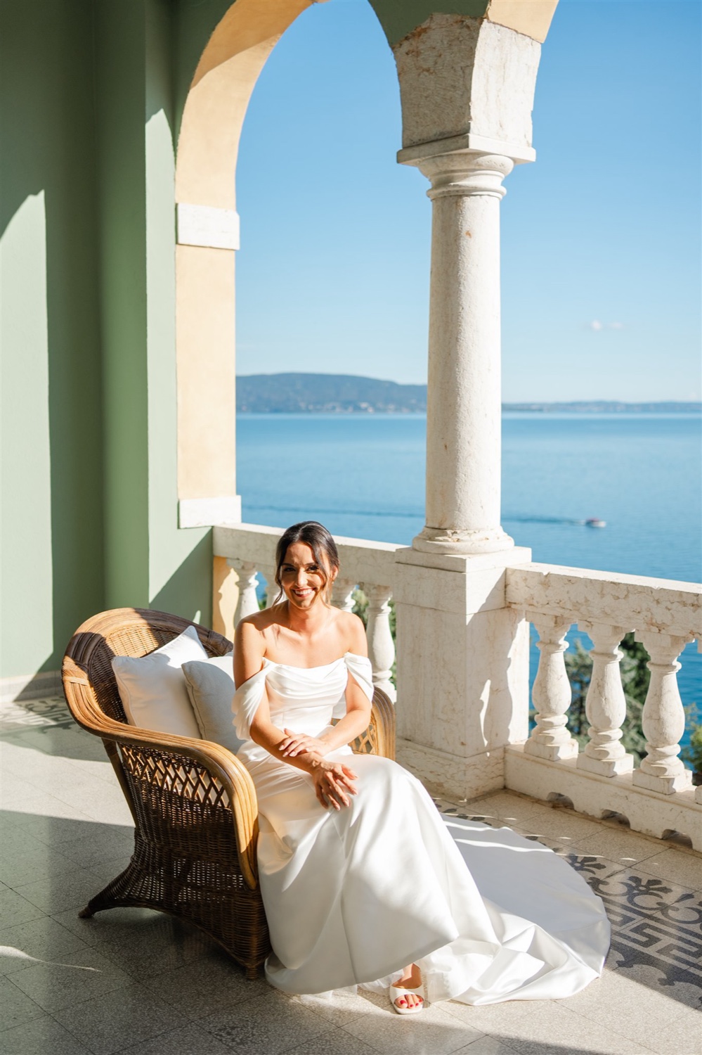A bride sitting in a wicker chair on the terrace of Villa del Sogno on Lake Garda