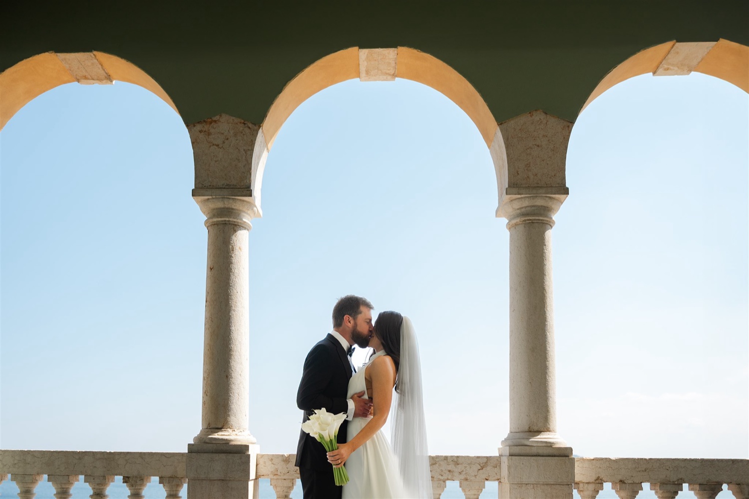 A couple kissing under the stone arches of the terrace at Villa del Sogno on Lake Garda