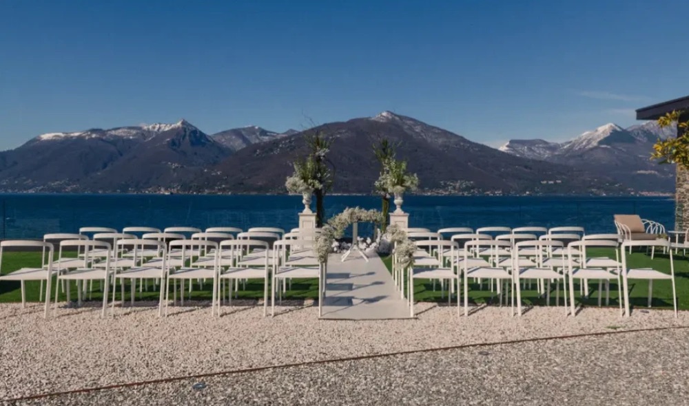 White chairs and a floral aisle set up for a ceremony on the terrace of Villa Porta, with snow-capped mountains across Lake Maggiore