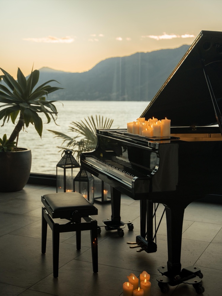 The terrace of Villa Porta at sunset with a grand piano, candles and a view over Lake Maggiore, Italy