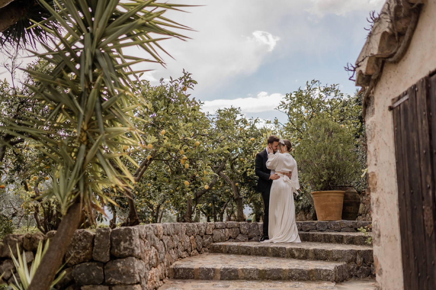 A couple embracing on the stone steps among the lemon trees at Ca’s Xorc in Mallorca