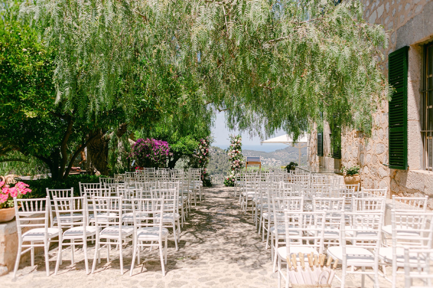 White chairs set out for a ceremony under the trees at Ca’s Xorc in Mallorca