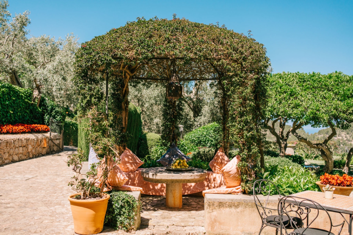 A garden pergola with a stone fire pit and cushions at Ca’s Xorc in Mallorca